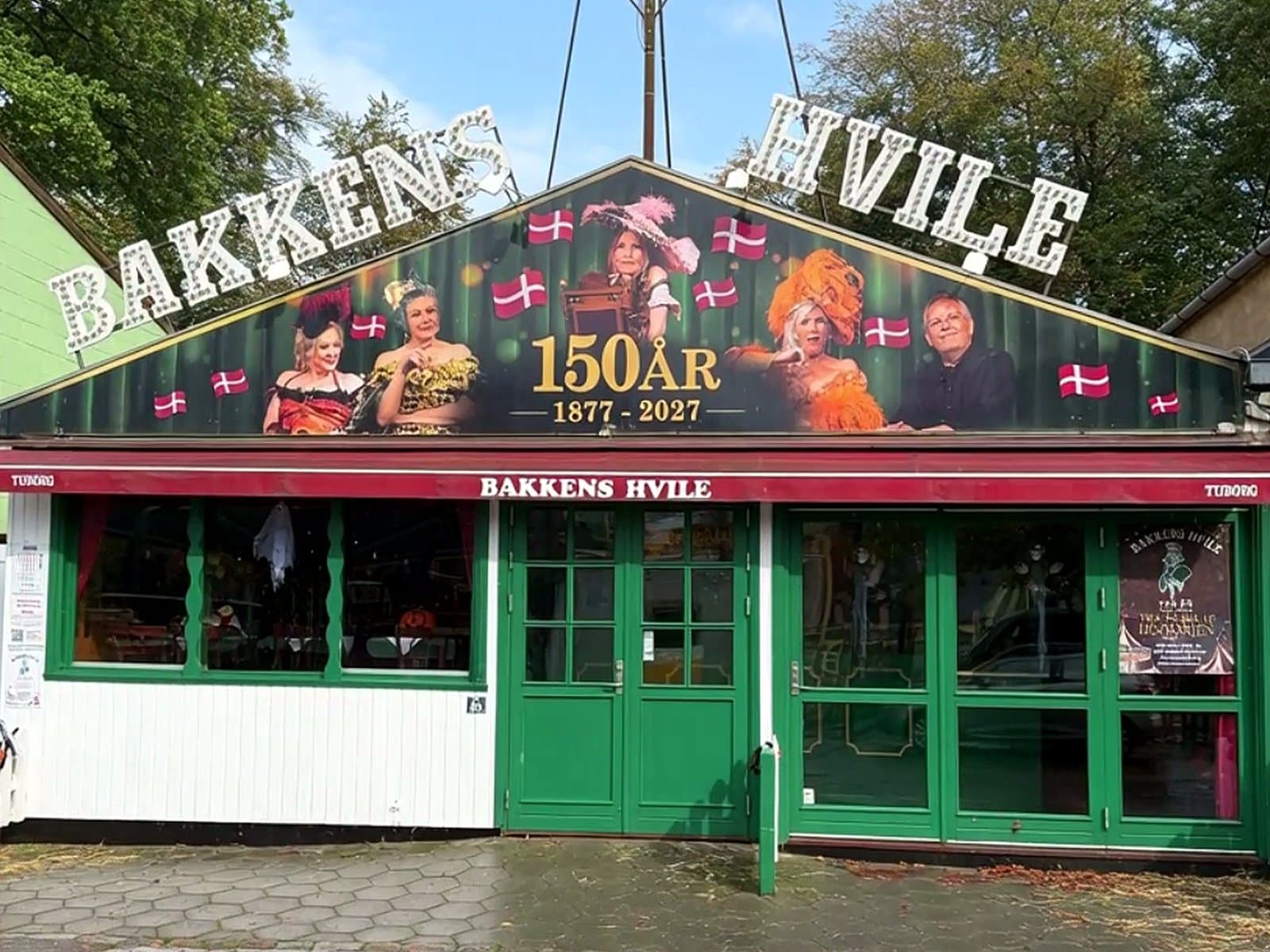 The green facade of Bakkens Hvile at Dyrehavsbakken with the neon figure on the roof